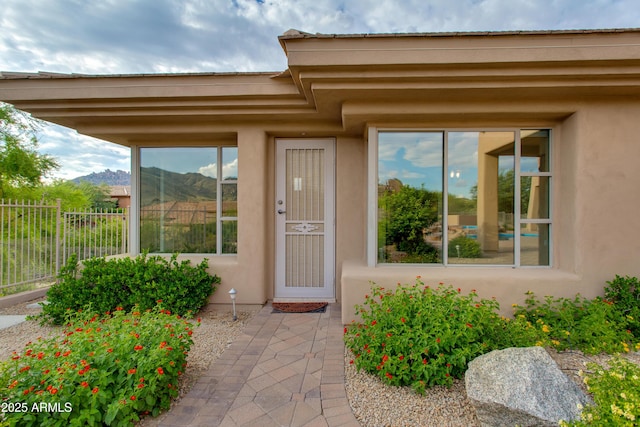 doorway to property with a patio area, fence, and stucco siding