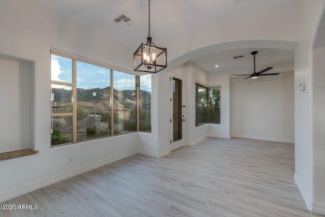 unfurnished dining area featuring light wood-type flooring, visible vents, a mountain view, and arched walkways