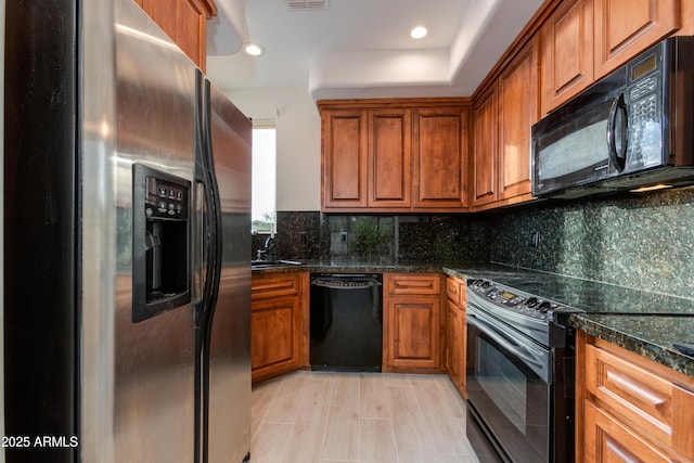 kitchen featuring dark stone counters, black appliances, brown cabinetry, and decorative backsplash