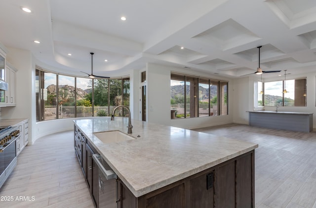 kitchen with dark brown cabinetry, appliances with stainless steel finishes, open floor plan, a kitchen island with sink, and a sink