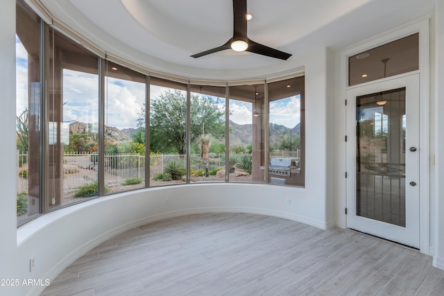 unfurnished sunroom with ceiling fan and a mountain view