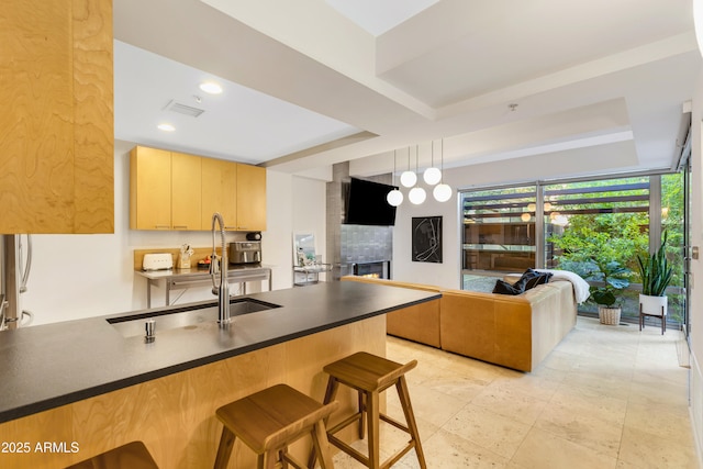 7131 E Rancho Vista Dr Unit 1008, Scottsdale, AZ 85251 - kitchen featuring dark countertops, a peninsula, a raised ceiling, a kitchen bar, and light brown cabinetry