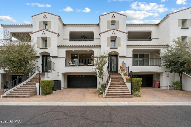 view of front facade featuring stairs, decorative driveway, an attached garage, and stucco siding