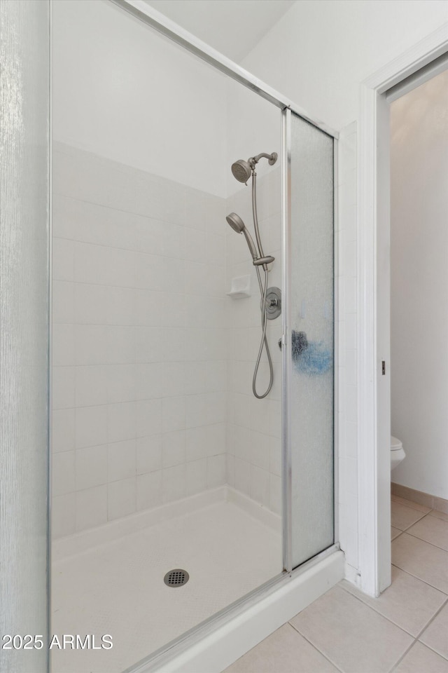 bathroom featuring an enclosed shower, tile patterned floors, and toilet