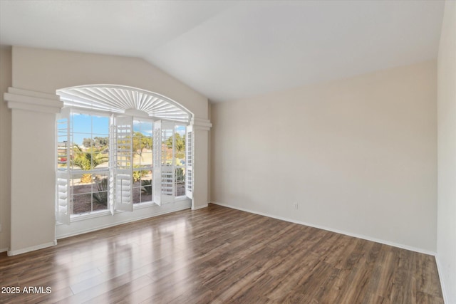 spare room with vaulted ceiling and dark wood-type flooring