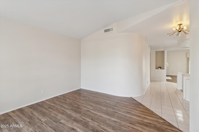 unfurnished room with an inviting chandelier, light hardwood / wood-style flooring, and lofted ceiling