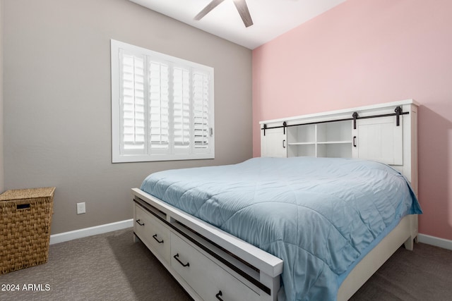 bedroom with a barn door, ceiling fan, and dark carpet