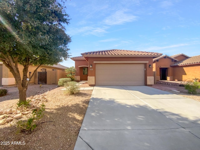 mediterranean / spanish-style home with a tiled roof, stucco siding, an attached garage, and concrete driveway