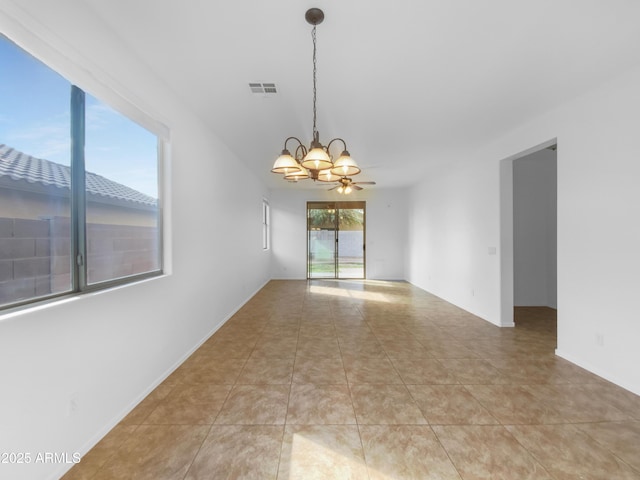 empty room with light tile patterned floors, visible vents, and ceiling fan with notable chandelier