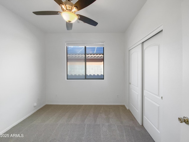 unfurnished bedroom with carpet flooring, baseboards, a closet, and ceiling fan