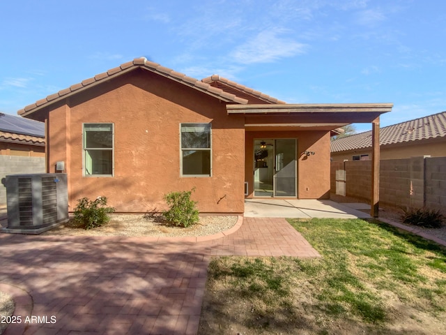 back of property with stucco siding, a patio, a tile roof, and fence