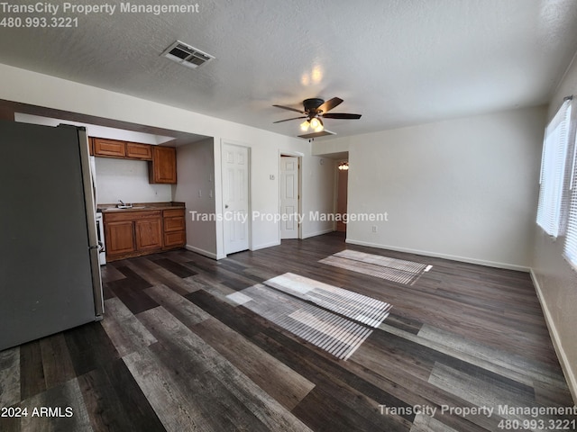 unfurnished living room with ceiling fan, dark hardwood / wood-style flooring, a textured ceiling, and sink