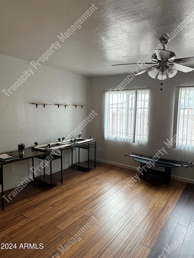 misc room with ceiling fan, wood-type flooring, and a textured ceiling