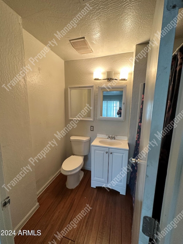 bathroom with toilet, vanity, a textured ceiling, and hardwood / wood-style flooring