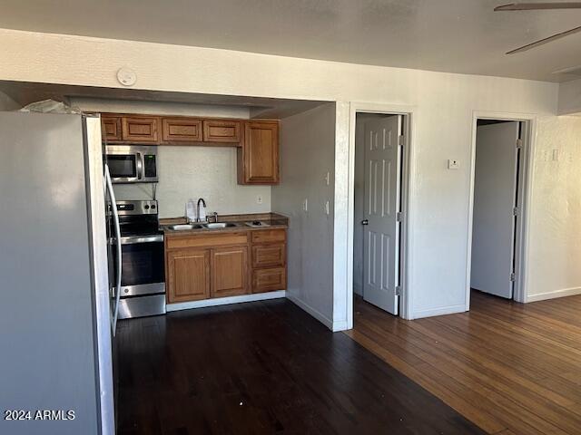 kitchen featuring dark hardwood / wood-style floors, ceiling fan, sink, and appliances with stainless steel finishes