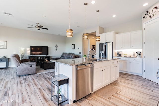 kitchen featuring white cabinetry, a center island with sink, stainless steel appliances, and decorative light fixtures