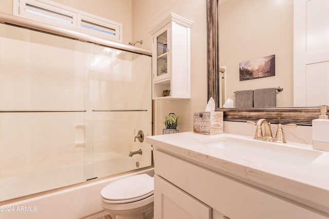 full bathroom with combined bath / shower with glass door, vanity, and toilet