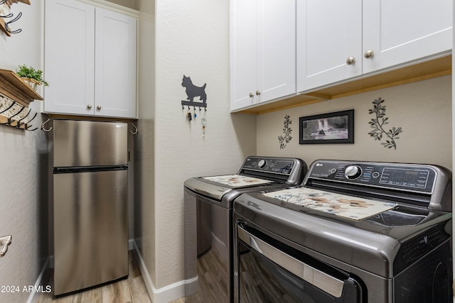 laundry area with independent washer and dryer, cabinets, and light hardwood / wood-style floors