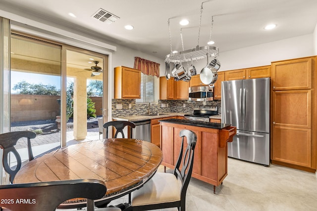 kitchen with backsplash, stainless steel appliances, ceiling fan, sink, and a center island