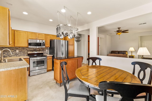 kitchen with ceiling fan, sink, tasteful backsplash, light tile patterned floors, and appliances with stainless steel finishes