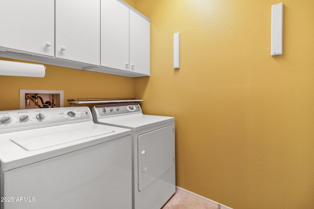 clothes washing area featuring cabinets, washer and clothes dryer, and light tile patterned flooring