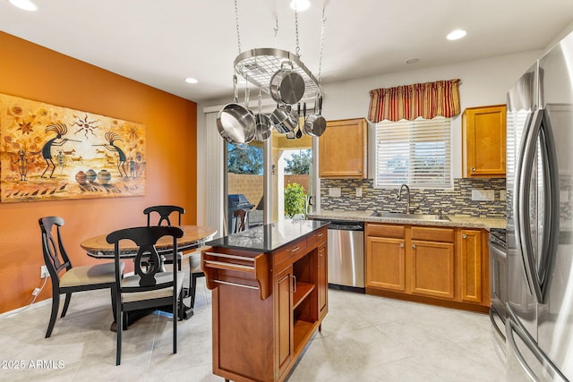 kitchen featuring decorative backsplash, appliances with stainless steel finishes, sink, dark stone countertops, and a kitchen island