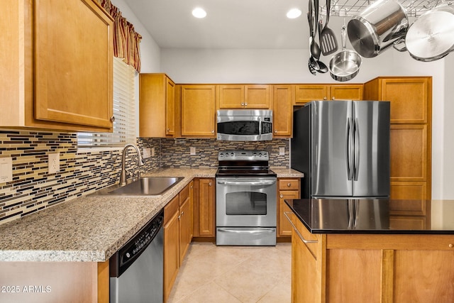 kitchen featuring light stone countertops, appliances with stainless steel finishes, tasteful backsplash, sink, and light tile patterned floors