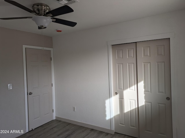 unfurnished bedroom with hardwood / wood-style flooring, ceiling fan, and a closet