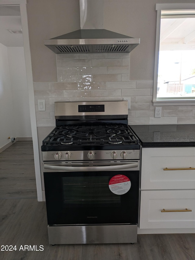 kitchen featuring white cabinets, wall chimney exhaust hood, backsplash, and stainless steel range with gas stovetop