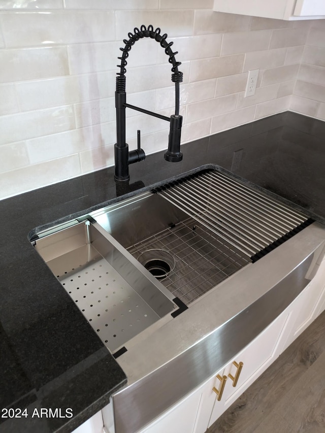 interior details with decorative backsplash, hardwood / wood-style flooring, white cabinets, and sink