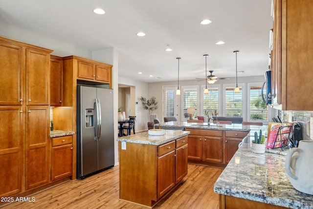 28351 N 130th Dr, Peoria, AZ 85383 - kitchen featuring appliances with stainless steel finishes, brown cabinetry, light wood-style flooring, recessed lighting, and a center island