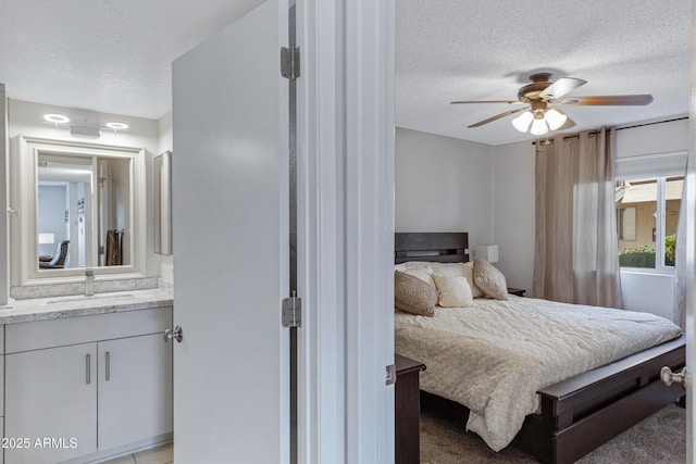 bedroom featuring a textured ceiling, a ceiling fan, and a sink