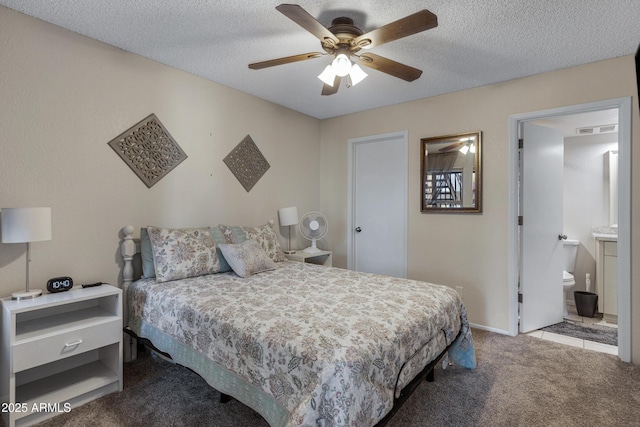 carpeted bedroom featuring ceiling fan, visible vents, a textured ceiling, and ensuite bathroom