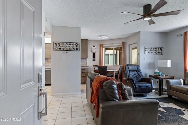 living room featuring a ceiling fan, light tile patterned flooring, a textured ceiling, and baseboards