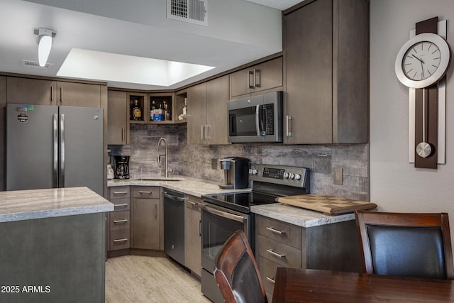 kitchen featuring tasteful backsplash, visible vents, stainless steel appliances, and a sink