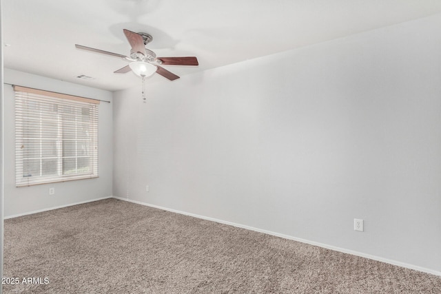 carpeted spare room featuring visible vents, ceiling fan, and baseboards