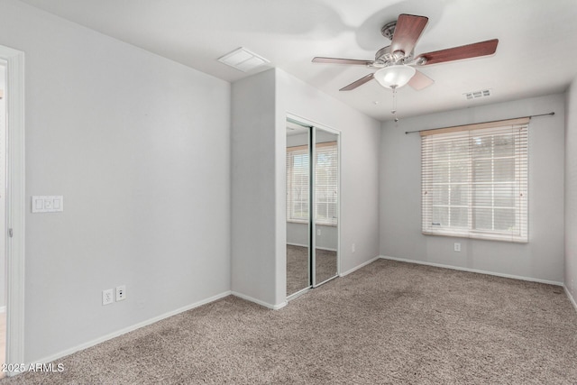 carpeted spare room featuring baseboards, visible vents, and a ceiling fan