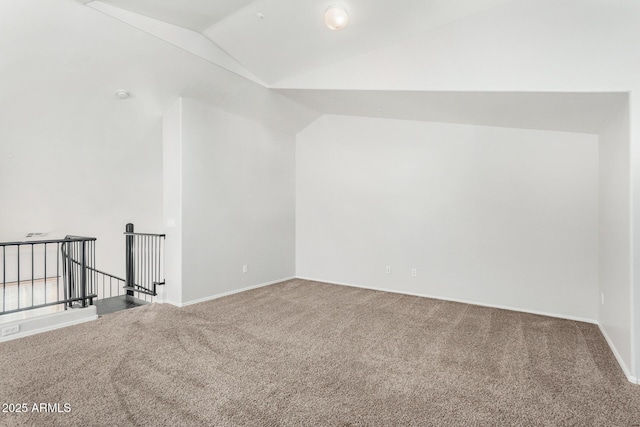 carpeted empty room featuring lofted ceiling and baseboards