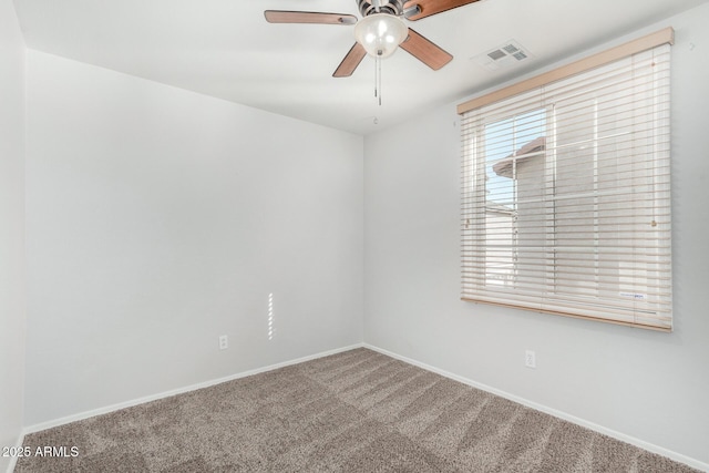 carpeted empty room with baseboards, visible vents, and a ceiling fan