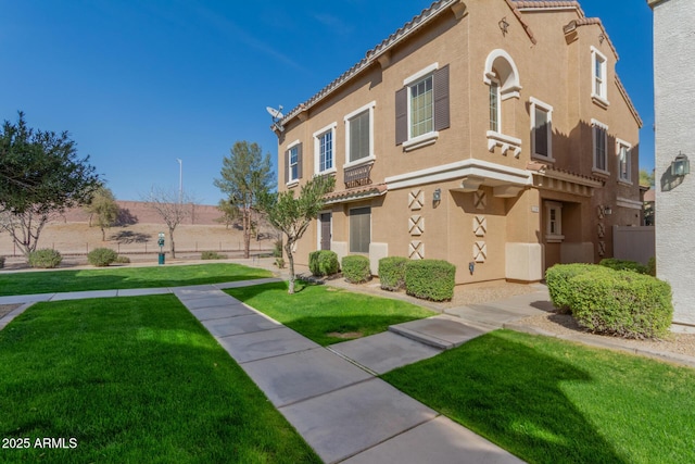 view of front of property with a front lawn, a tile roof, and stucco siding