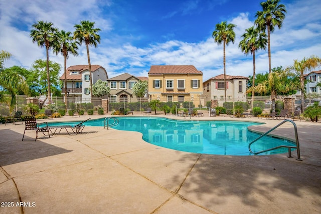 community pool featuring a patio, fence, and a residential view