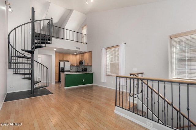 interior space with high vaulted ceiling, baseboards, and hardwood / wood-style floors