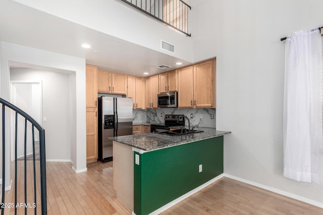 kitchen with visible vents, baseboards, appliances with stainless steel finishes, light wood-type flooring, and decorative backsplash