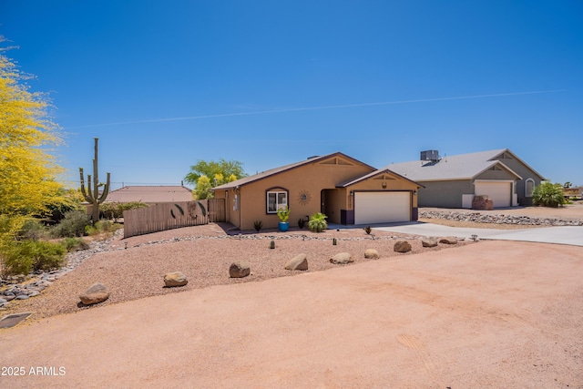 ranch-style house featuring a garage, fence, stucco siding, and driveway