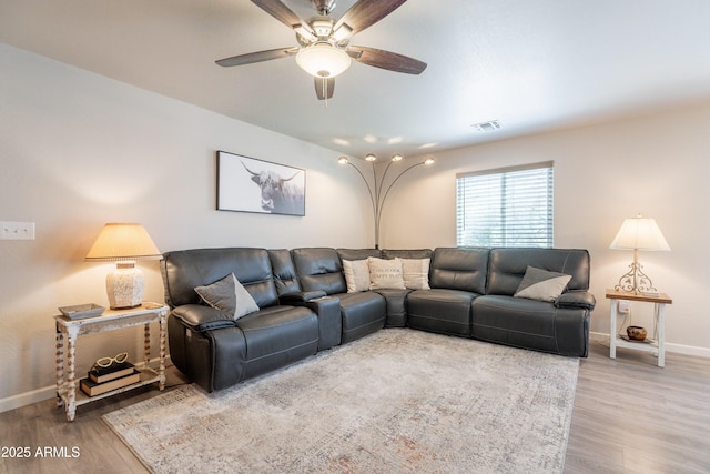 living room featuring baseboards, ceiling fan, and wood finished floors