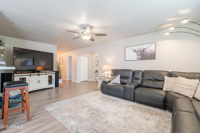 living room with baseboards, arched walkways, a ceiling fan, and wood finished floors