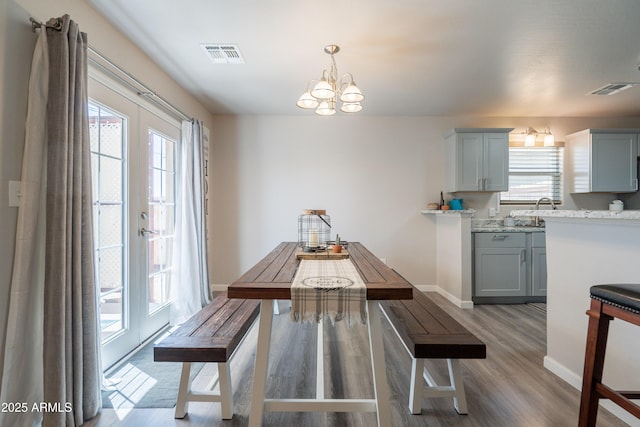 dining area featuring an inviting chandelier, baseboards, wood finished floors, and visible vents