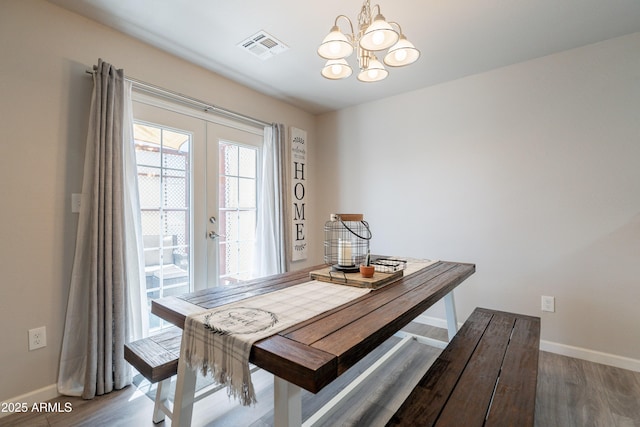 dining space featuring baseboards, visible vents, an inviting chandelier, and light wood-style flooring