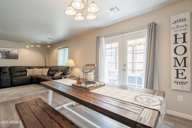 dining area featuring an inviting chandelier, french doors, wood finished floors, and visible vents