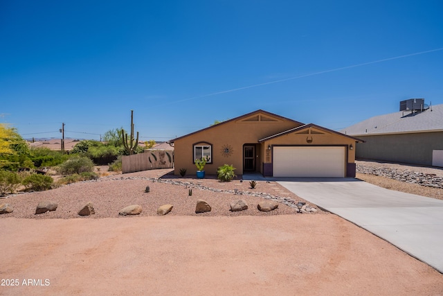 view of front of property featuring concrete driveway, an attached garage, central AC unit, and stucco siding